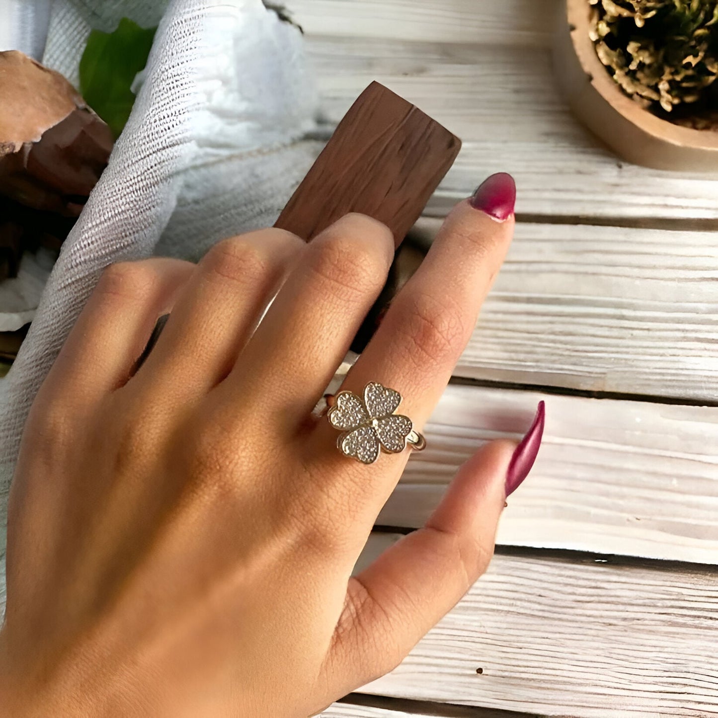 Bague rotative en acier doré et oxydes de zirconium portée au doigt d'une femme vue du dessus.