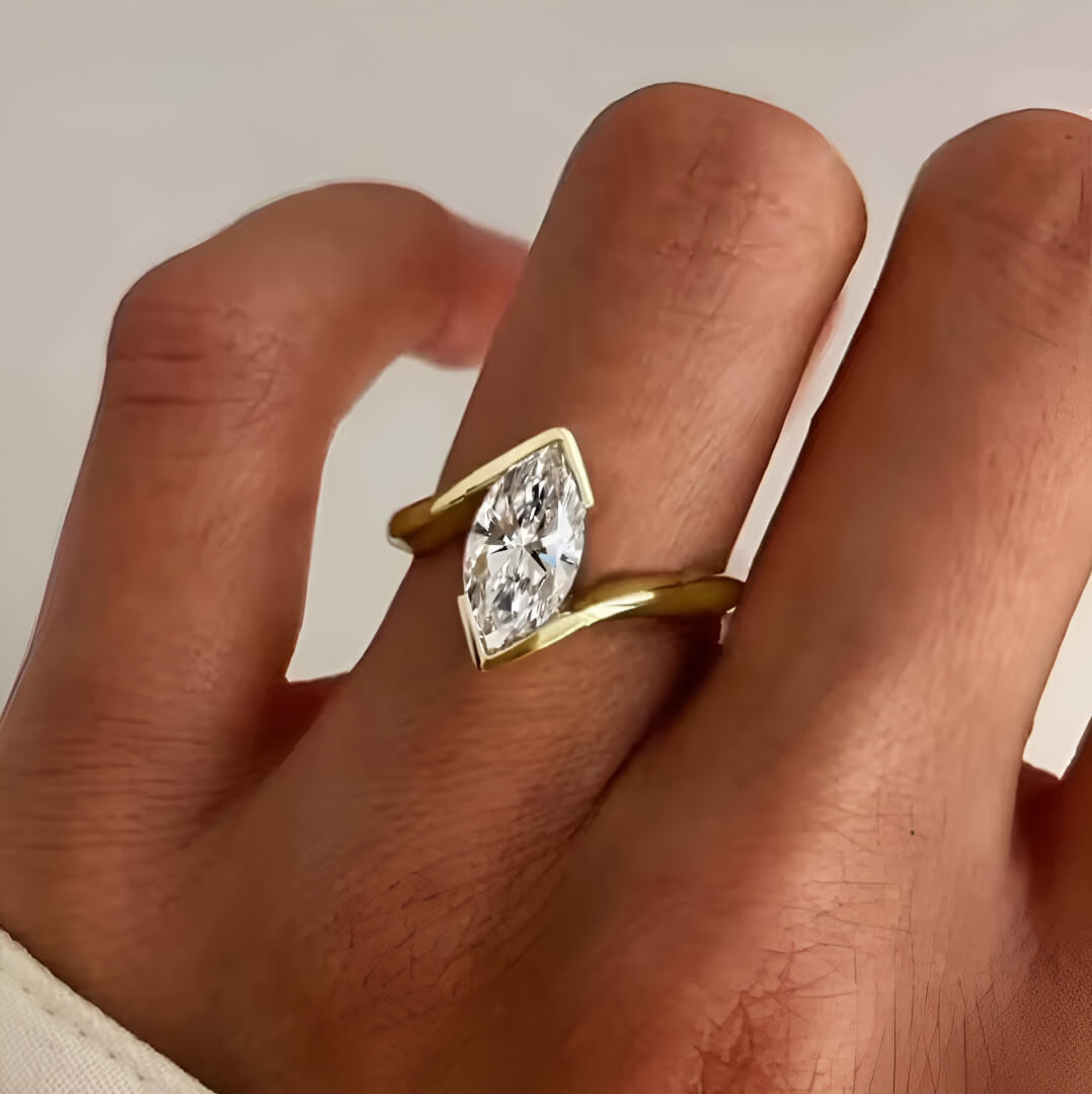 Bague solitaire en or jaune et diamant synthétique portée qu doigt d'une femme.