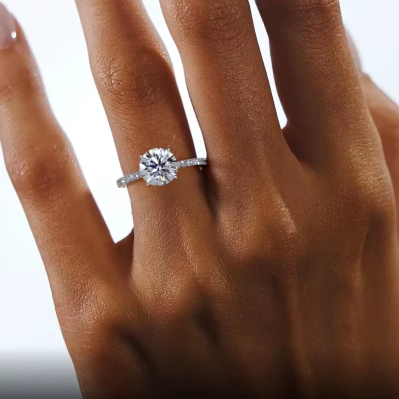 Bague solitaire en or blanc et diamants naturels et synthétiques portée au doigt d'une femme vue du dessus.