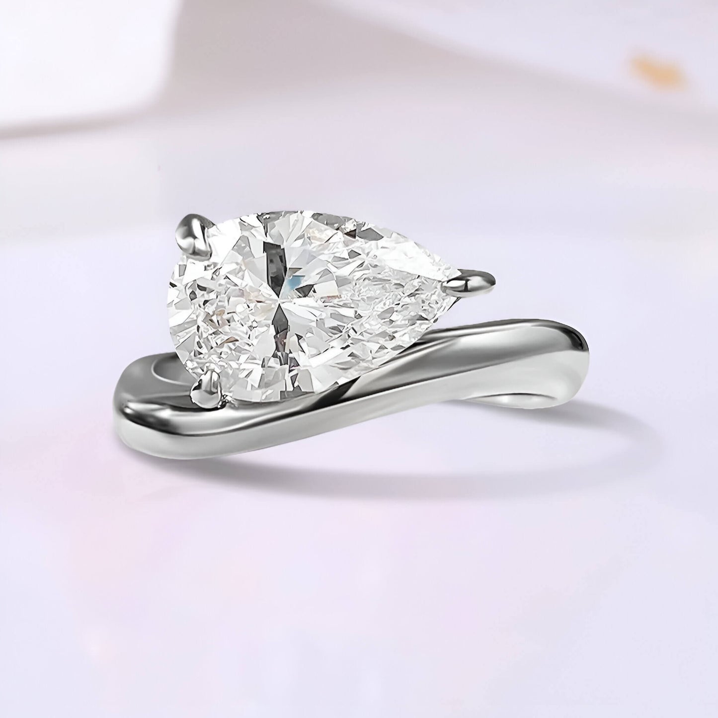 Bague solitaire courbée en or blanc et diamant synthétique sur fond uni.