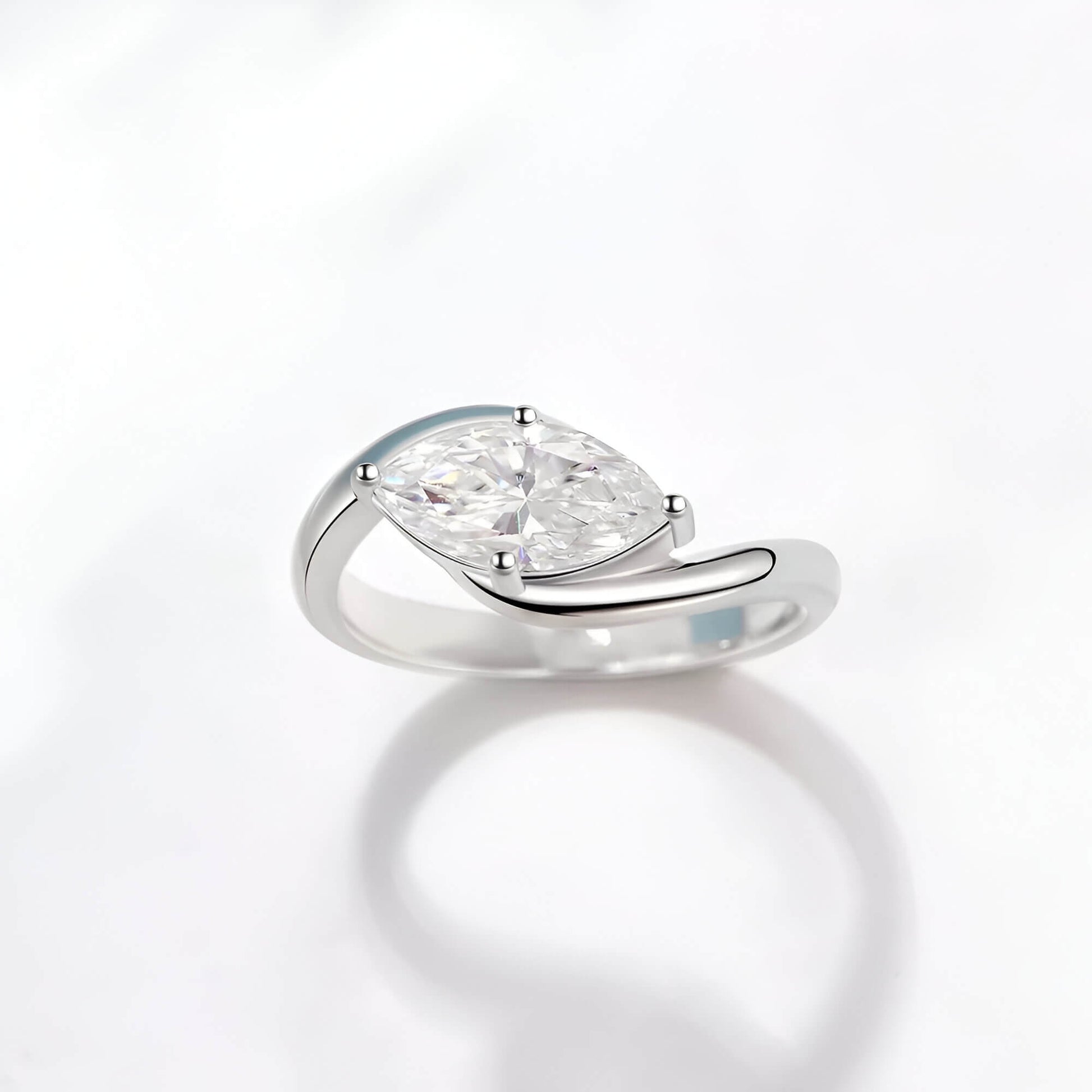 Bague solitaire courbée en or blanc et diamant synthétique sur fond blanc.