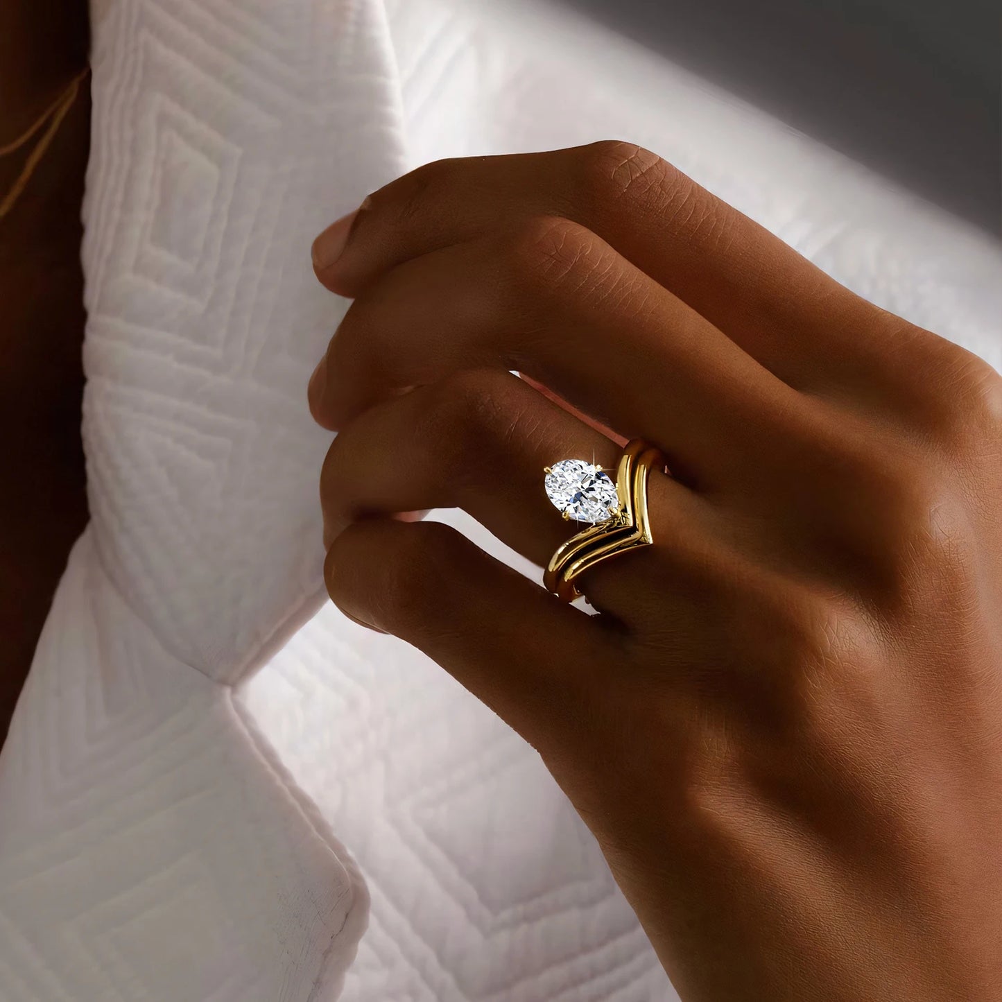 Bague solitaire en or jaune et diamant synthétique portée au doigt d'une femme.