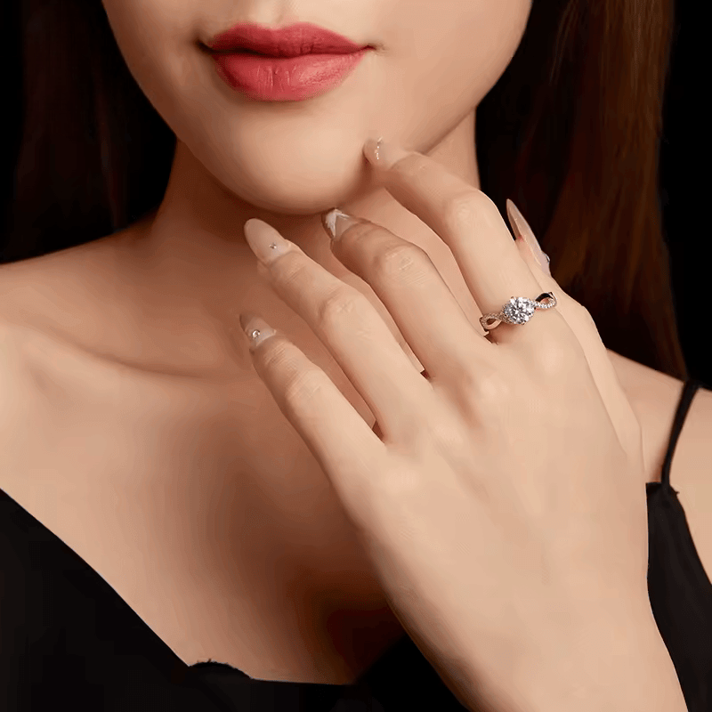 Bague solitaire courbée en or blanc et diamants synthétiques portée au doigt d'une femme.