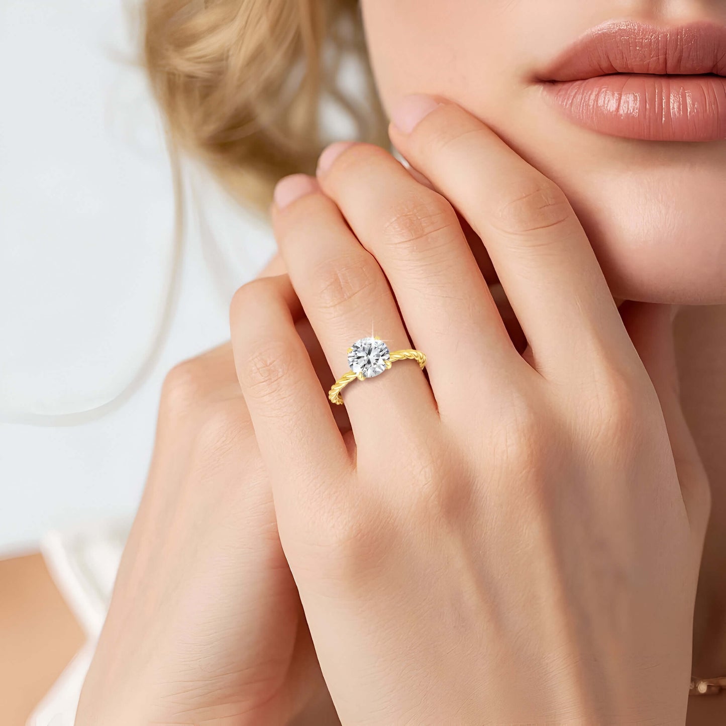 Bague solitaire ondulée en or jaune et diamant synthétique portée au doigt d'une femme.