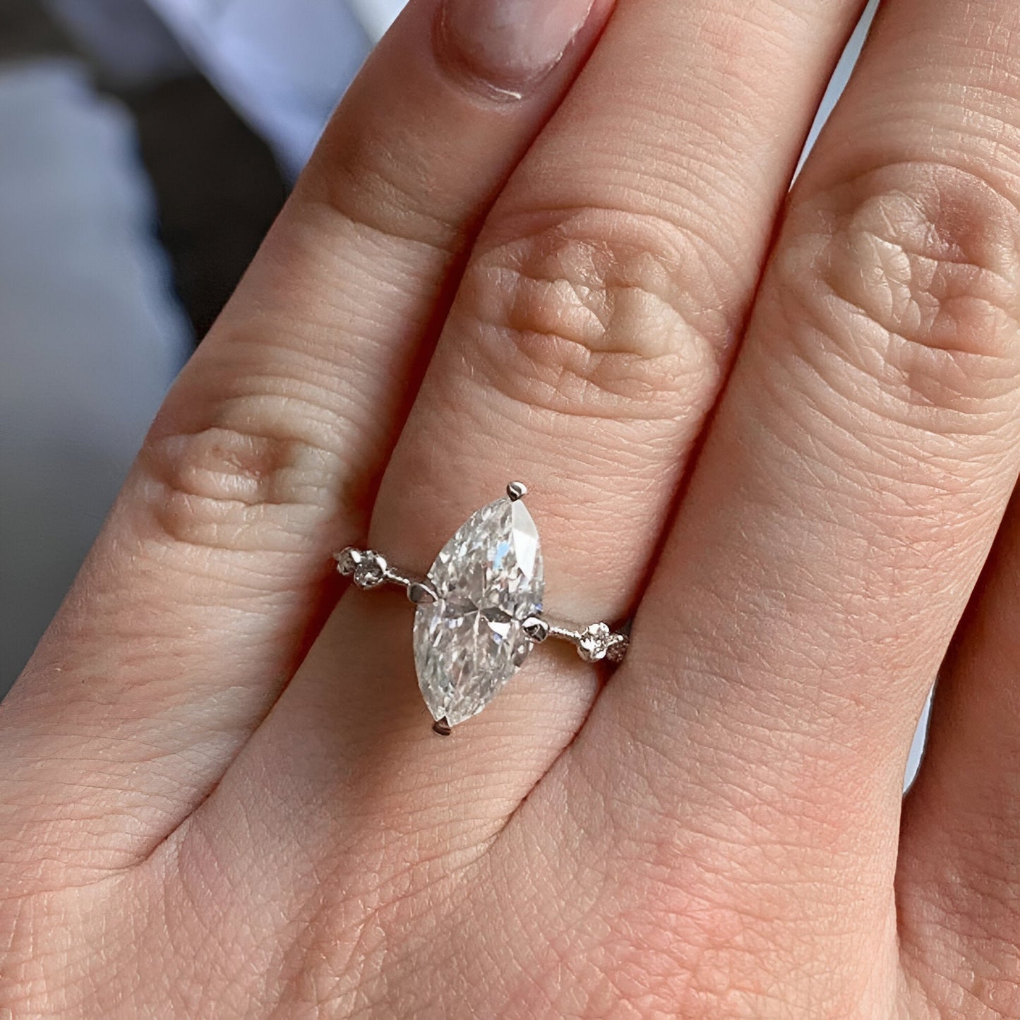 Bague solitaire en or blanc et oxyde de zirconium portée au doigt d'une femme vue du dessus.