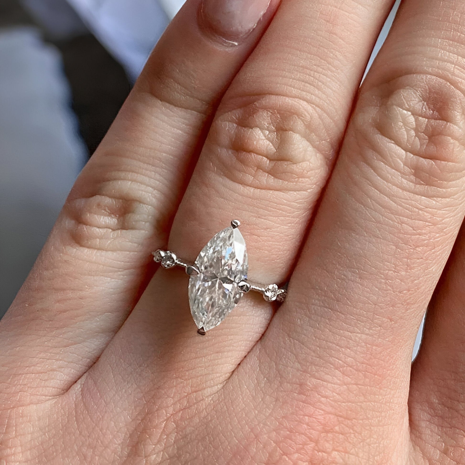 Bague solitaire en or blanc et oxyde de zirconium portée au doigt d'une femme vue du dessus.