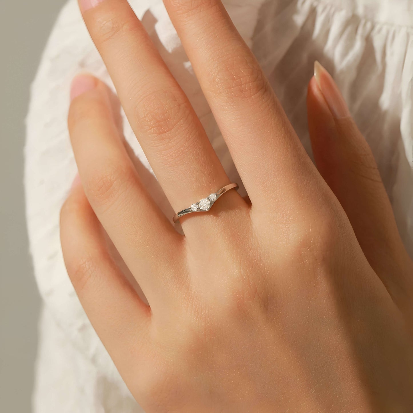 Bague trilogie Etherea en argent 925 plaqué or blanc et diamants portée au doigt d'une femme.