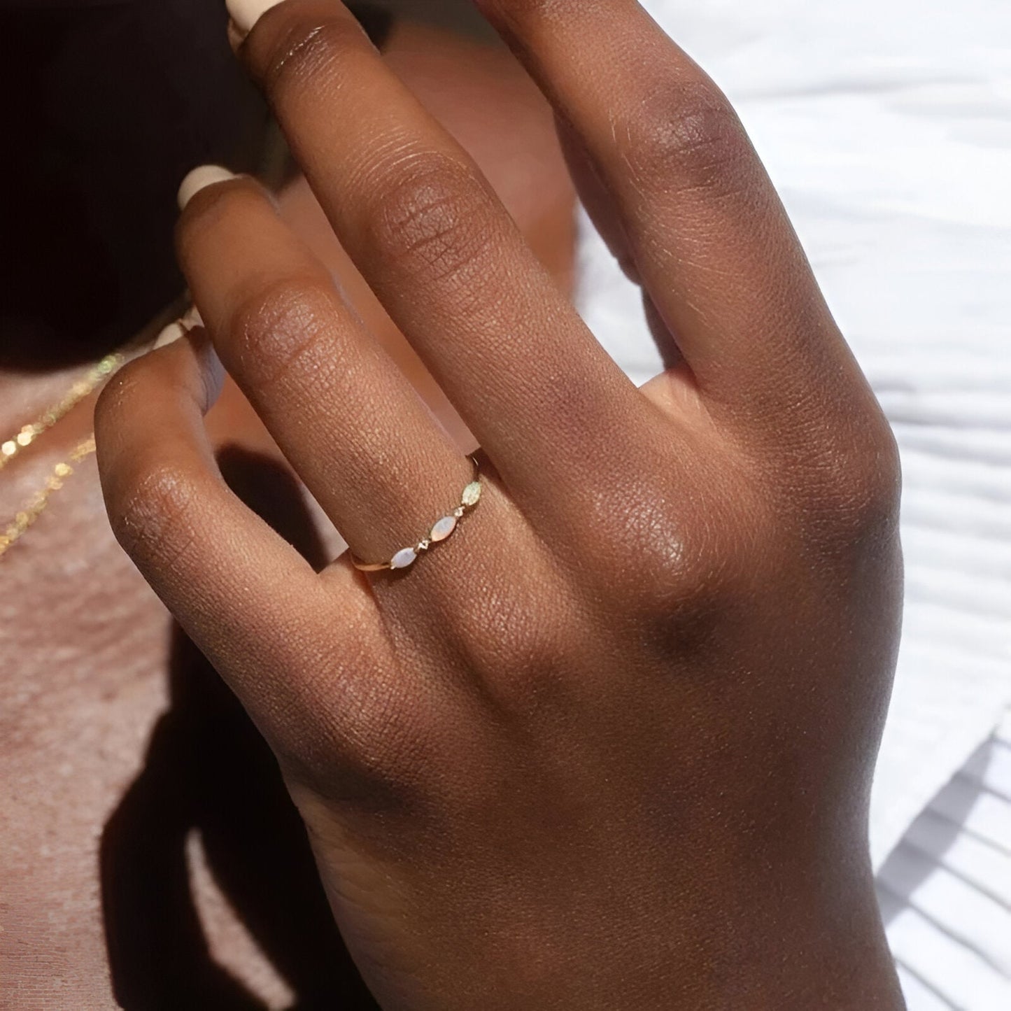 Bague triple opale fine Aurantis en argent 925 plaqué or jaune et diamants portée au doigt d'une femme vue de face.