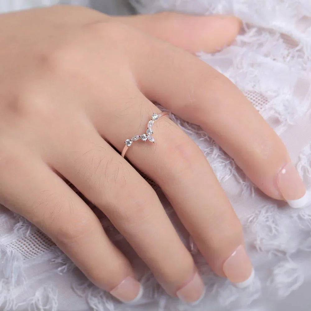 Bague V sept pierres en acier inoxydable plaqué or blanc et diamants brillants portée au doigt d'une femme vue de proche.