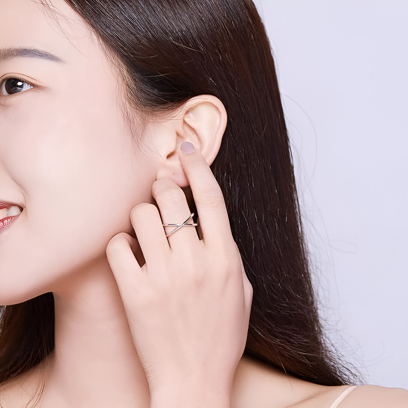 Bague X en or blanc portée au doigt d'une femme.