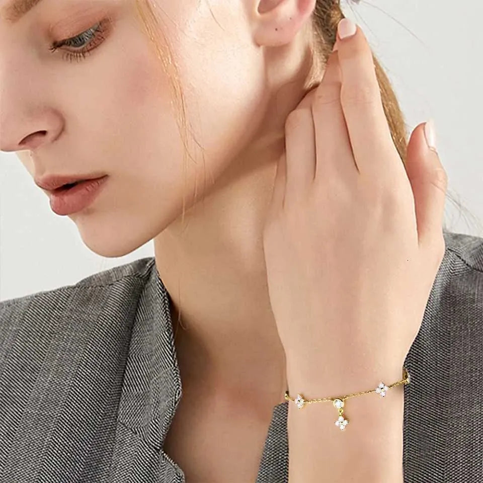 Bracelet breloque fleur en argent 925 plaqué or jaune raffiné et diamants porté au poignet d'une femme.