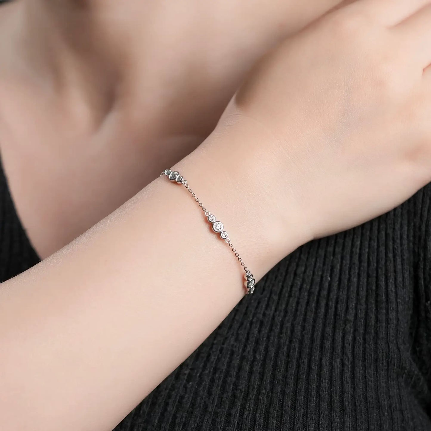 Bracelet chaîne sinueuse trio de pierres en argent 925 plaqué or blanc discret et moissanites porté au poignet d'une femme vue de proche.