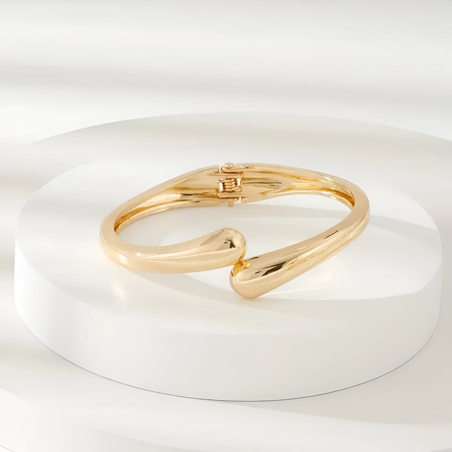 Bracelet courbe enlacée en alliage de zinc et or 14k de face sur un socle - position allongée
