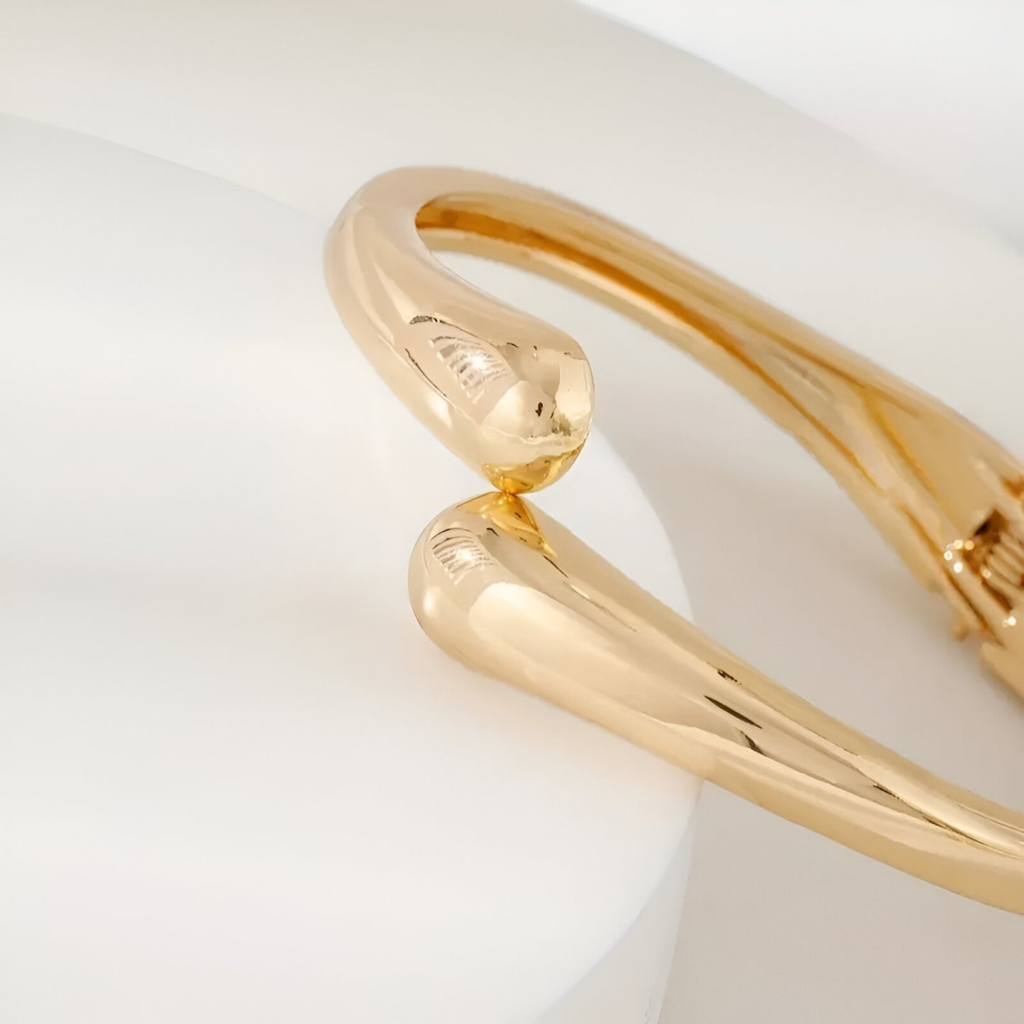 Détail du Bracelet courbe enlacée en alliage de zinc et plaquage or 14k sur un socle blanc - bijou luxueux