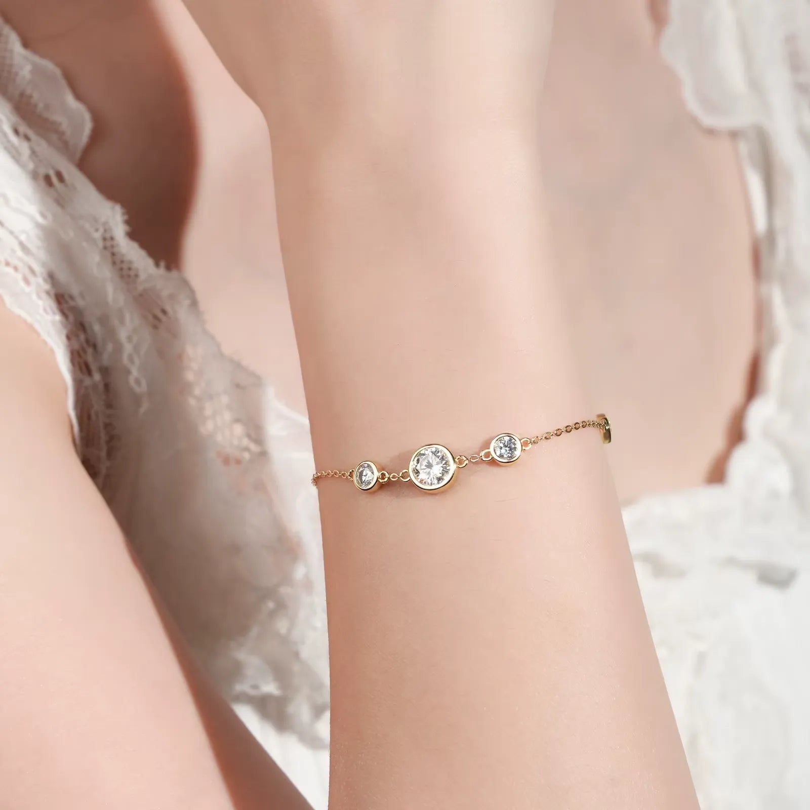 Chaîne cinq pierre en or jaune et diamants synthétiques portée au poignet d'une femme vue de face.