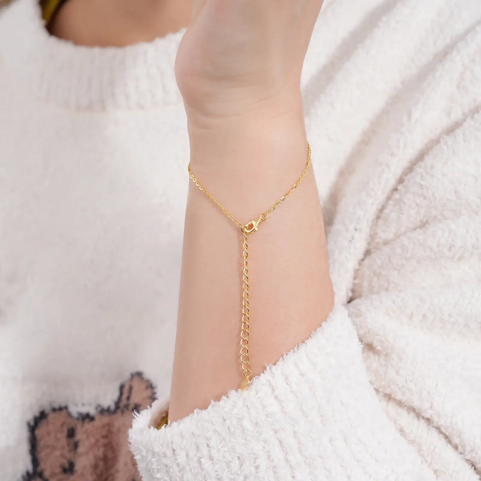 Chaîne fleur solitaire en or jaune et diamants synthétiques portée au poignet d'une femme vue de dos.