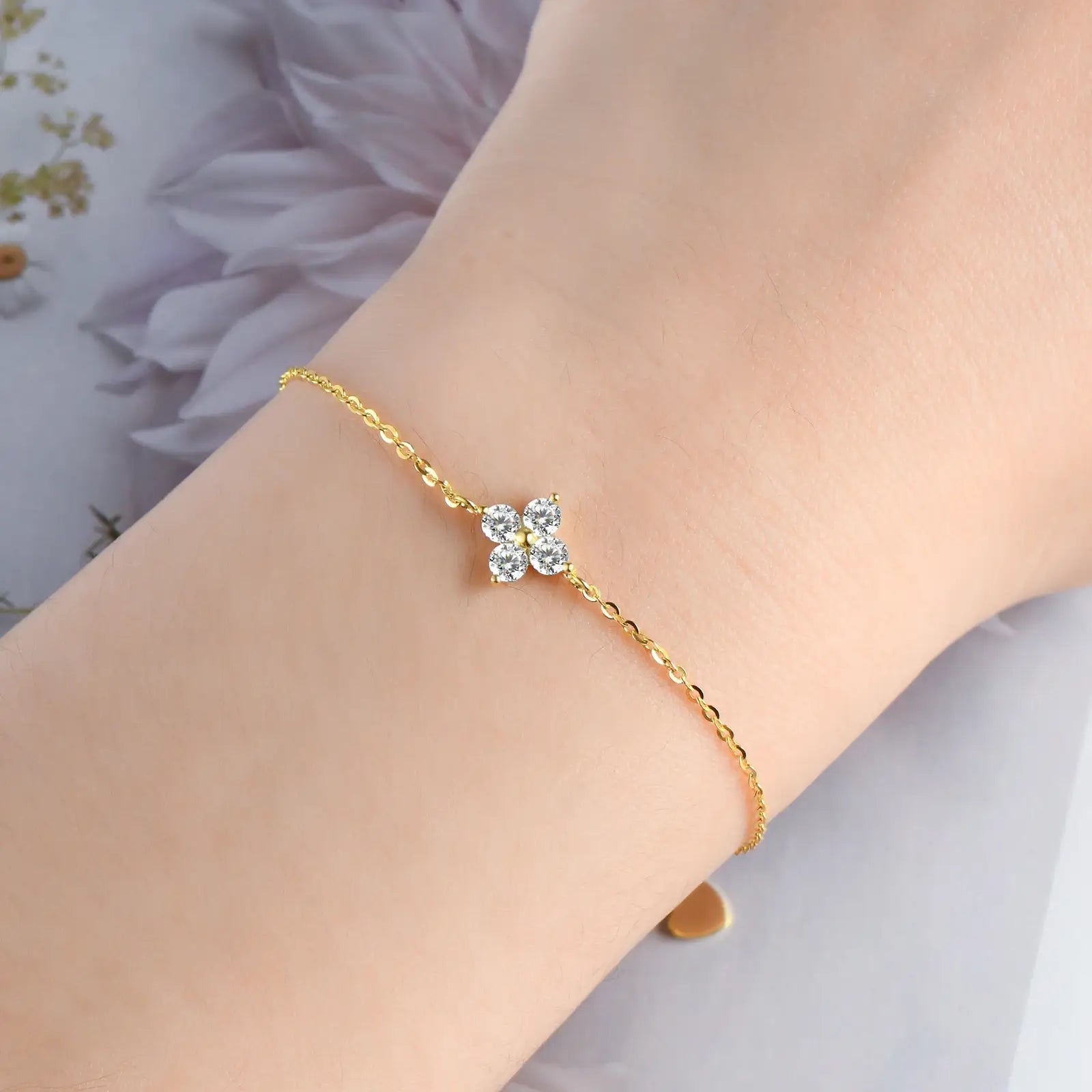 Chaîne fleur solitaire en or jaune et diamants synthétiques portée au poignet d'une femme.