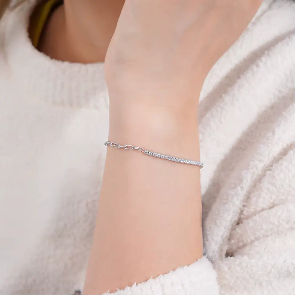 Chaîne maille cheval en or blanc et diamants synthétiques portée au poignet d'une femme.