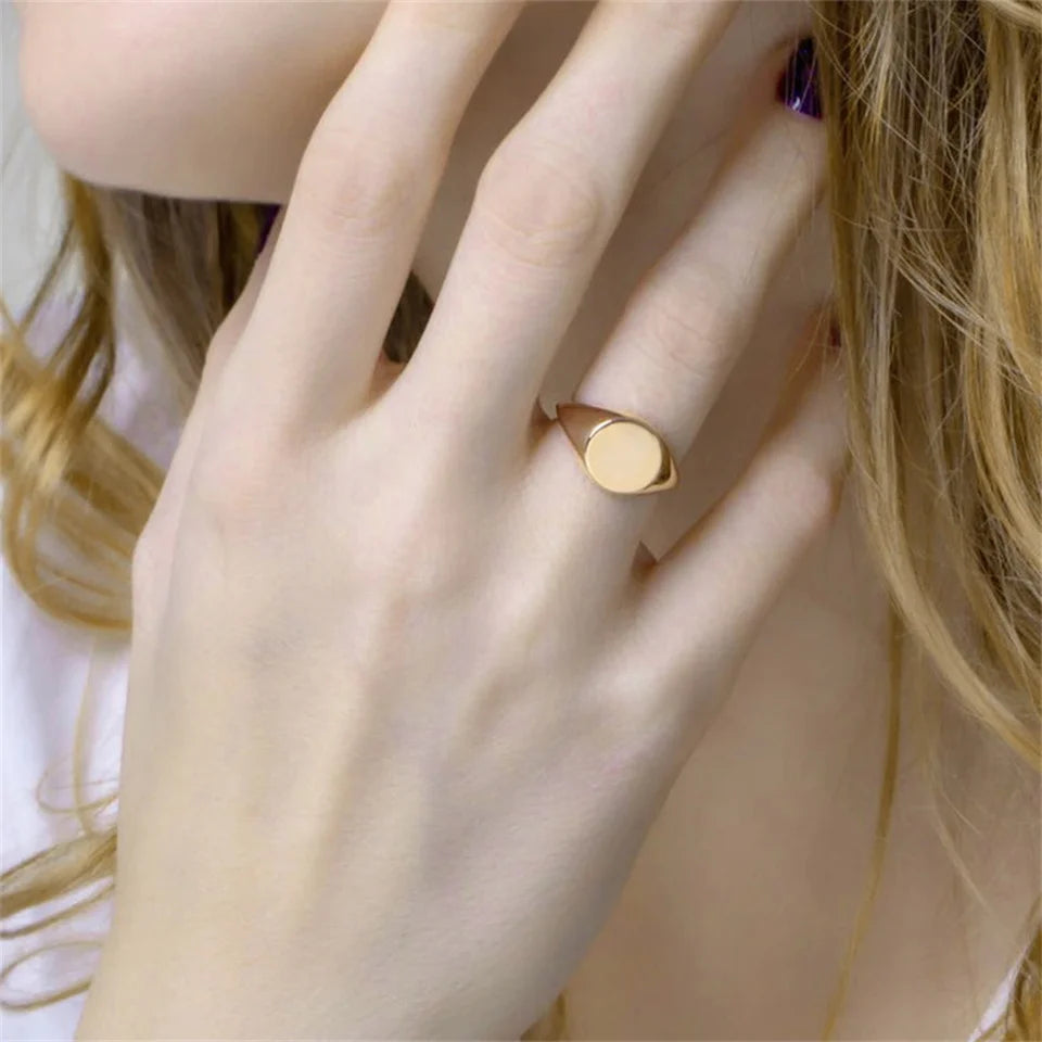 Chevalière pavé arrondi poli en acier inoxydable plaqué or jaune portée au doigt d'une femme vue de face.