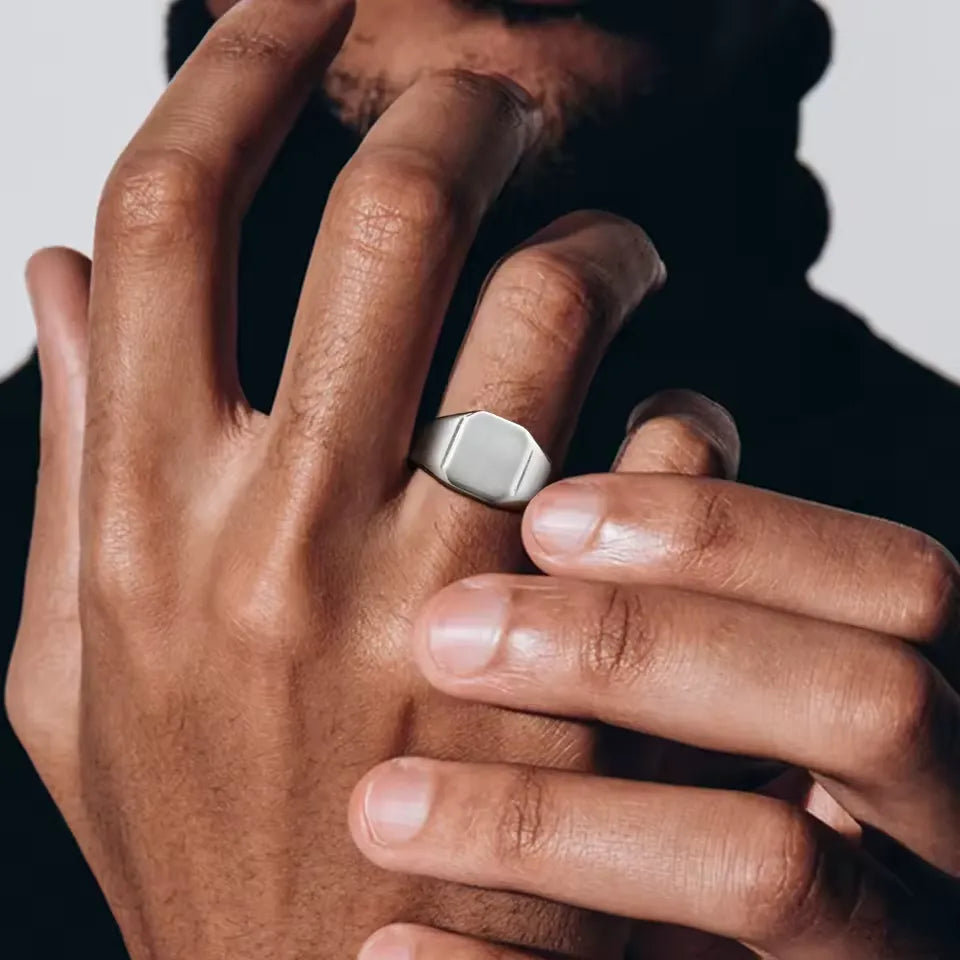 Chevalière pavé cubique poli en acier inoxydable plaqué titane portée au doigt d'un homme vue de face.