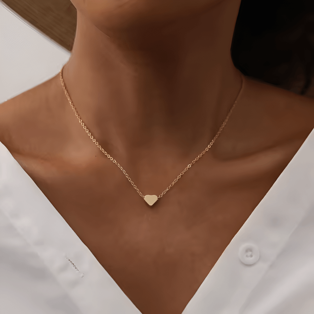 Collier fantaisie cœur en or jaune porté au cou d'une femme vue de face.