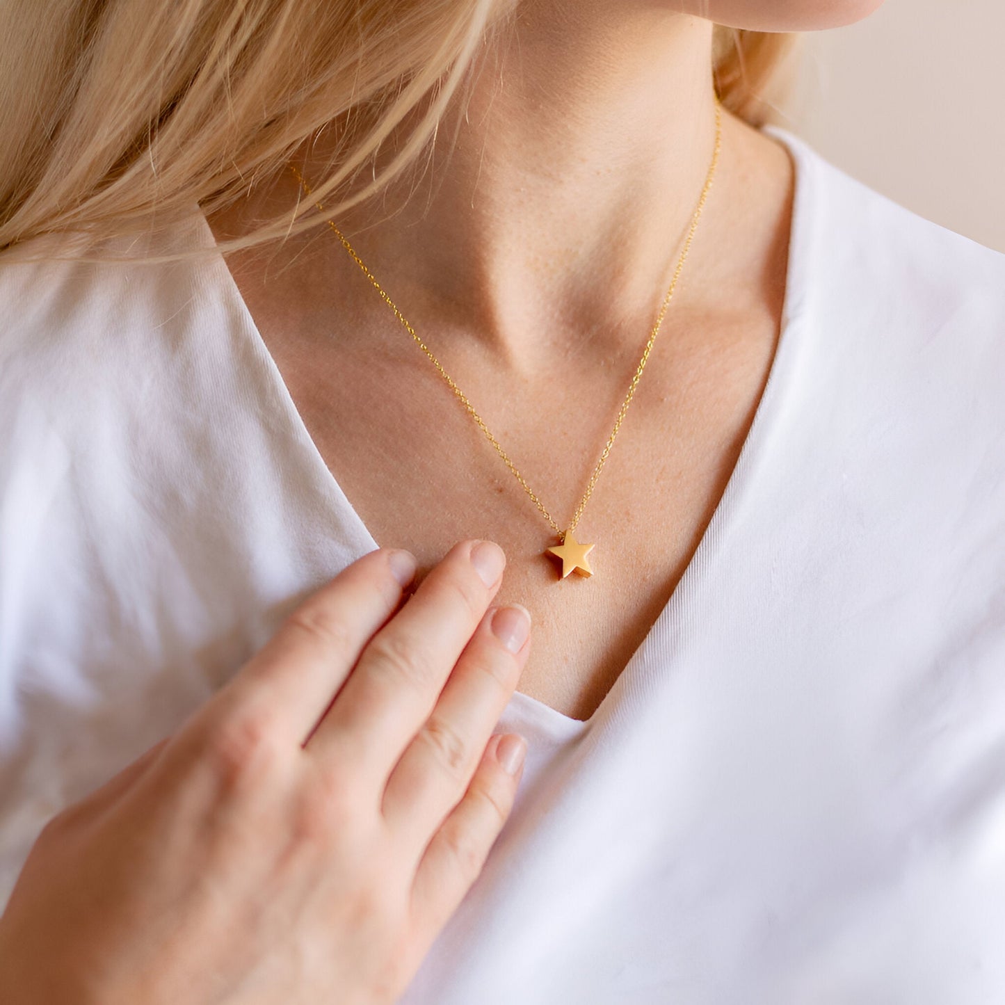 Collier fantaisie étoile en or jaune porté au cou d'une femme.