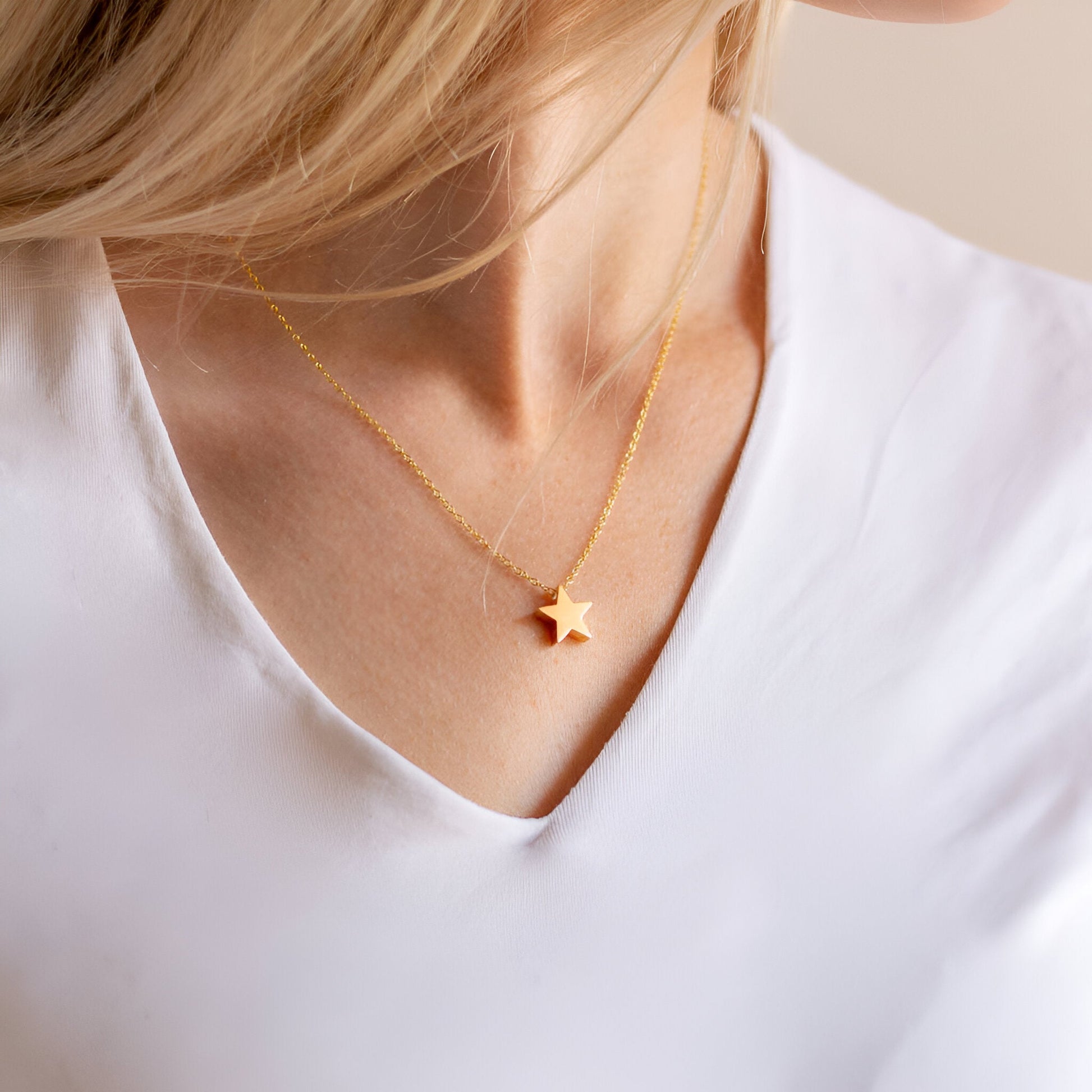 Collier fantaisie étoile en or jaune porté au cou d'une femme vue de face.