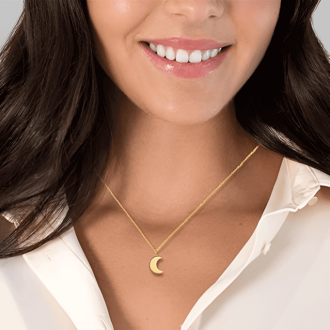 Collier fantaisie lune en or jaune porté au cou d'une femme vue de face.
