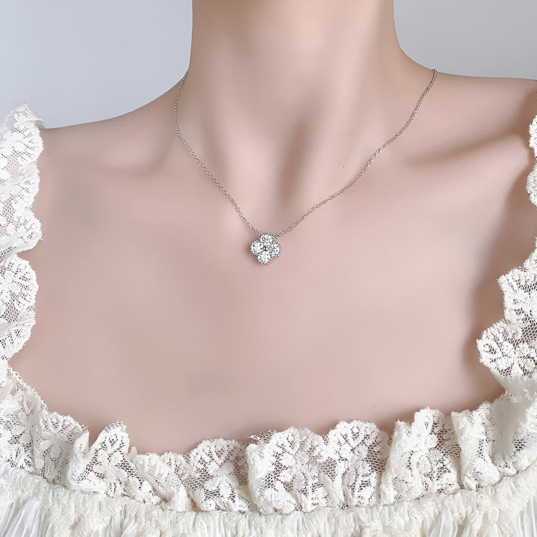 Femme chic portant autour du cou le collier Flora en argent sterling 925 avec pendentif moissanite éclatante en forme de fleur.