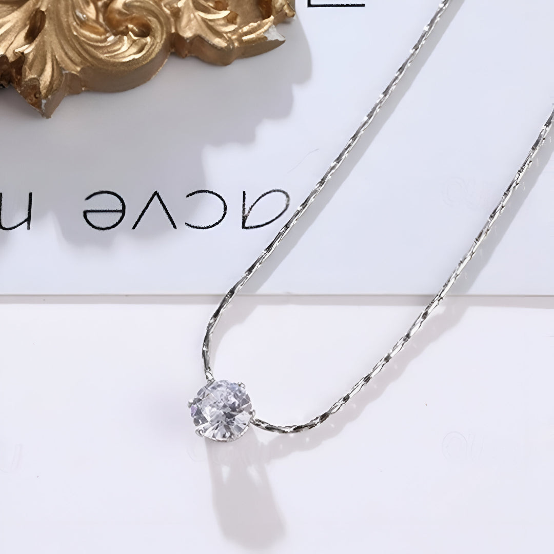 Collier solitaire lumière argentée posé à plat, zircon brillant sur chaîne plaquée or blanc