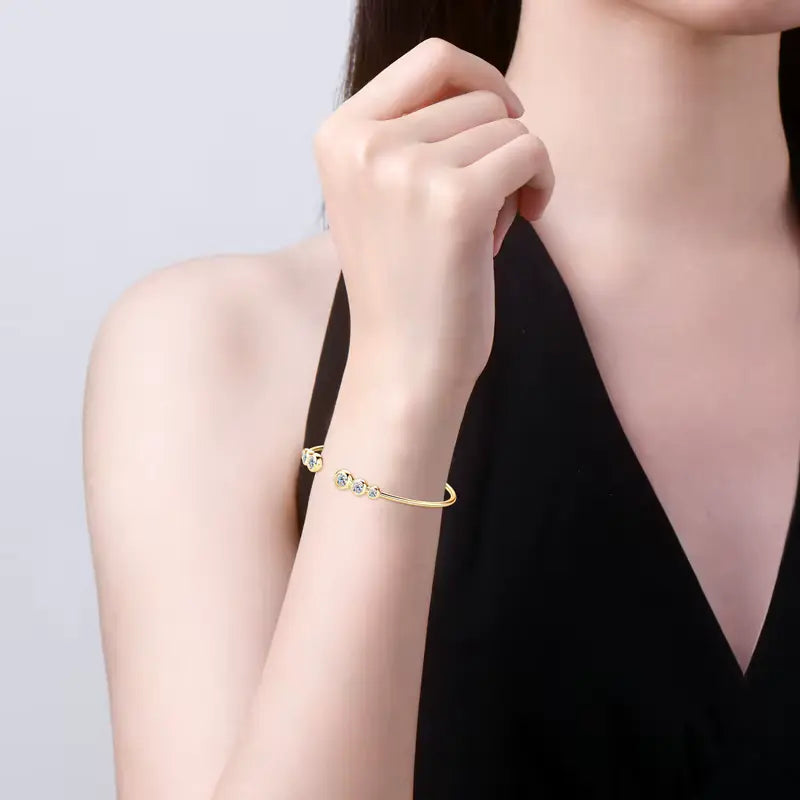 Bracelet jonc fin en argent sterling 925 plaqué or jaune et diamants porté au poignet d'une femme.