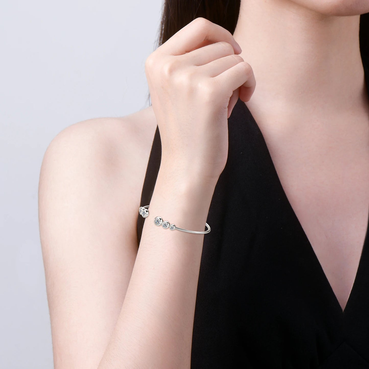 Jonc serti clos nathy en argent 925 plaqué or blanc et moissanites porté au poignet d'une femme vue de côté.