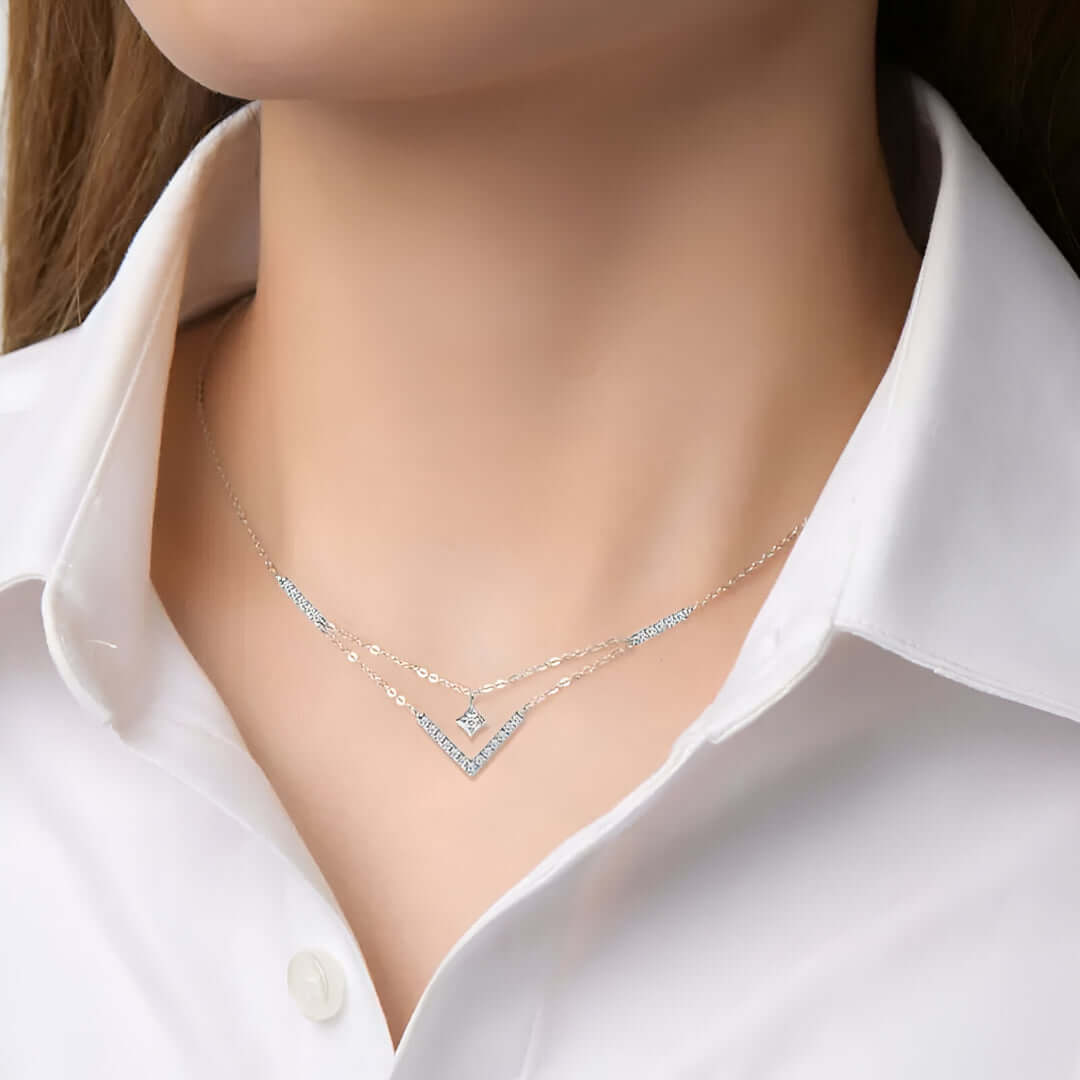 Multi-chaînes pendentif solitaire en or blanc et diamants synthétiques porté au cou d'une femme vue de face.