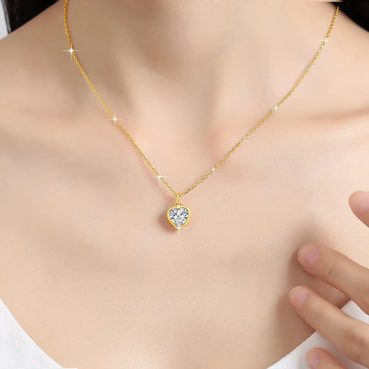 Pendentif cœur solitaire en or jaune et diamant synthétique porté au cou d'une femme.