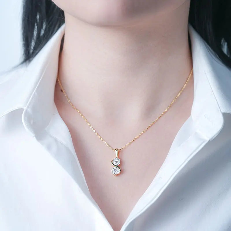 Pendentif courbé serti invisible en or jaune et diamants synthétiques porté au cou d'une femme vue de face.
