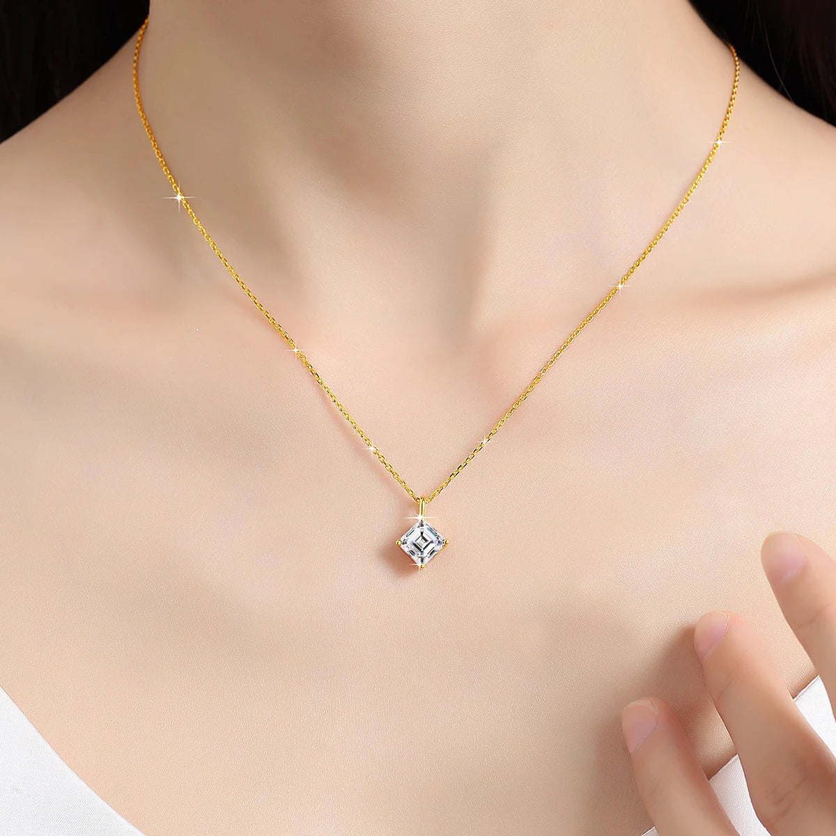 Pendentif solitaire asscher en or jaune et diamant synthétique porté au cou d'une femme.