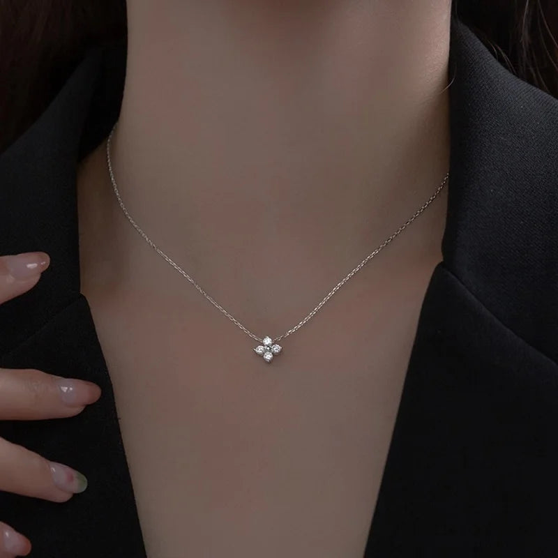 Pendentif solitaire en or blanc et diamants synthétiques porté au cou d'une femme.