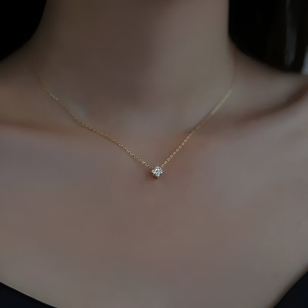 Pendentif solitaire en or jaune et diamants synthétiques porté au cou d'une femme.