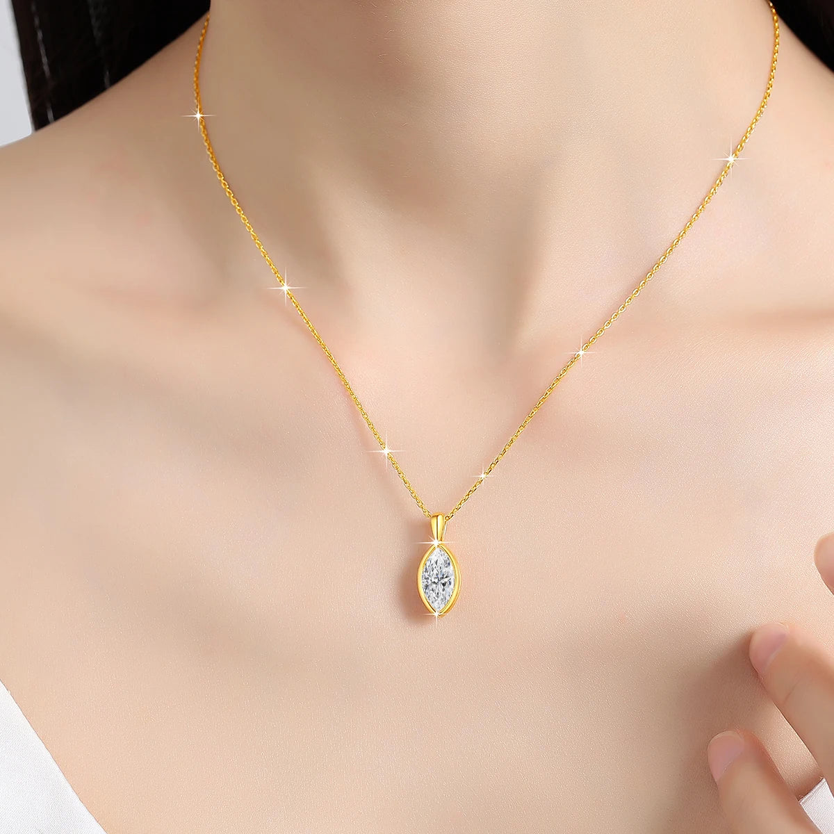 Pendentif solitaire navette en or jaune et diamant synthétique porté au cou d'une femme.