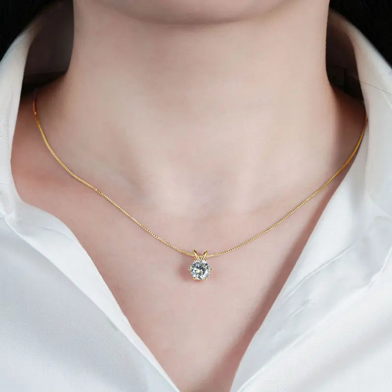 Pendentif solitaire serti six griffes en argent 925 plaqué or jaune et diamant 4ct éclatant porté au cou d'une femme vue de proche.
