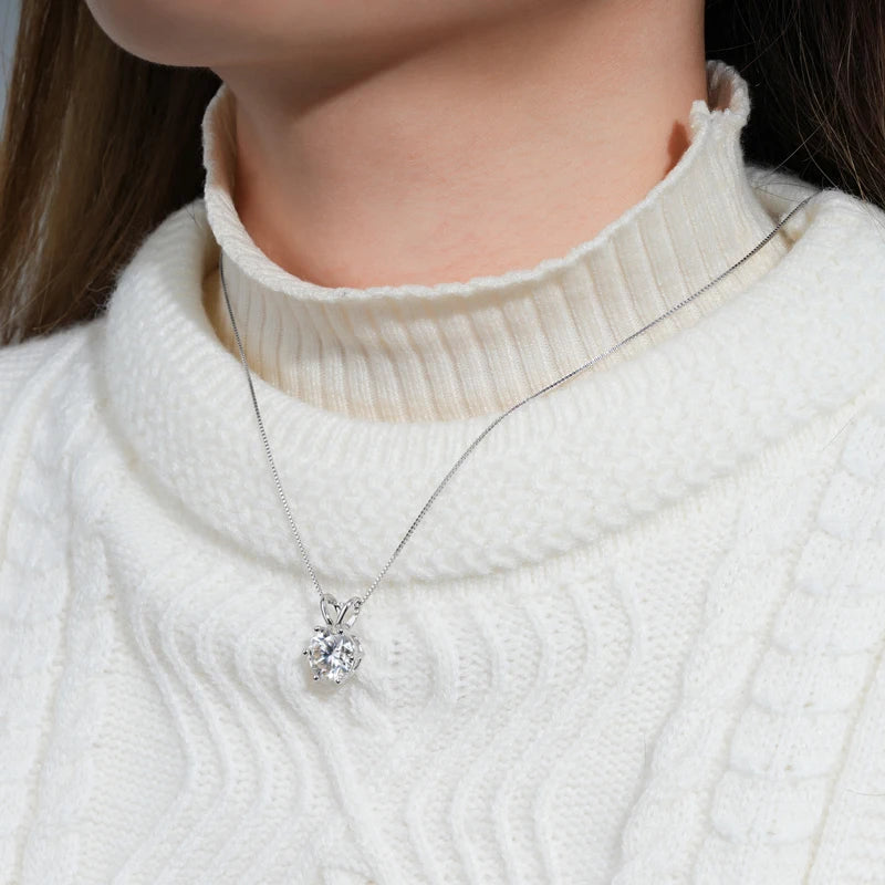 Collier pendentif solitaire en or blanc et diamant synthétique porté au cou d'une femme vue de proche.