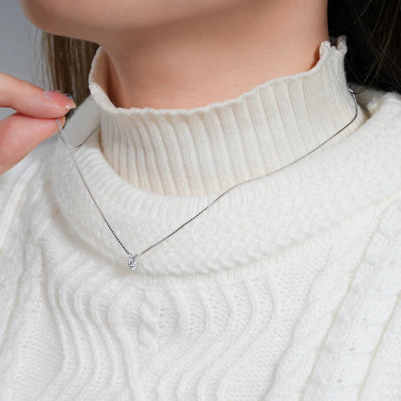 Collier pendentif solitaire en or blanc et diamant synthétique porté au cou d'une femme vue de côté.