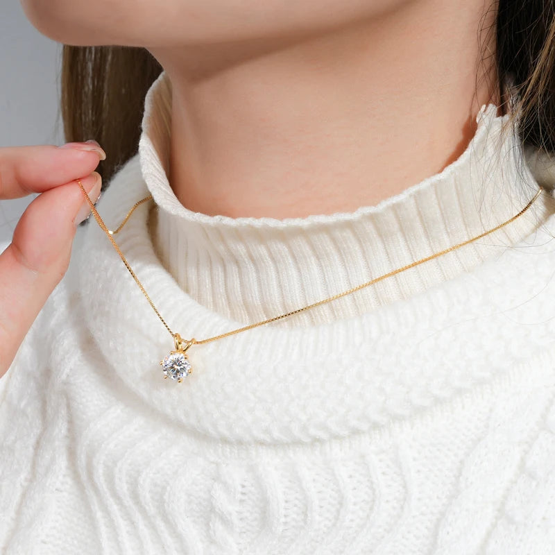 Collier pendentif solitaire en or jaune et diamant synthétique porté au cou d'une femme vue de côté.