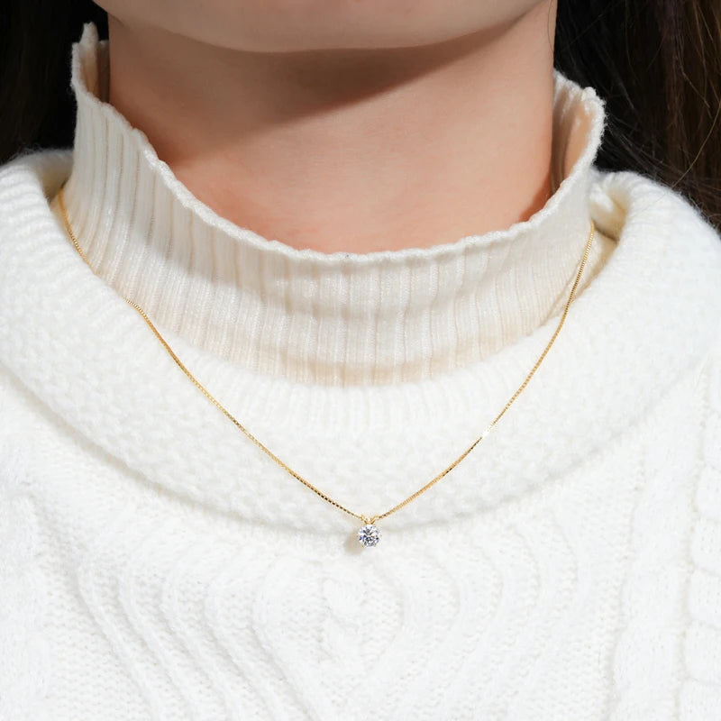 Collier pendentif solitaire en or jaune et diamant synthétique porté au cou d'une femme vue de face.