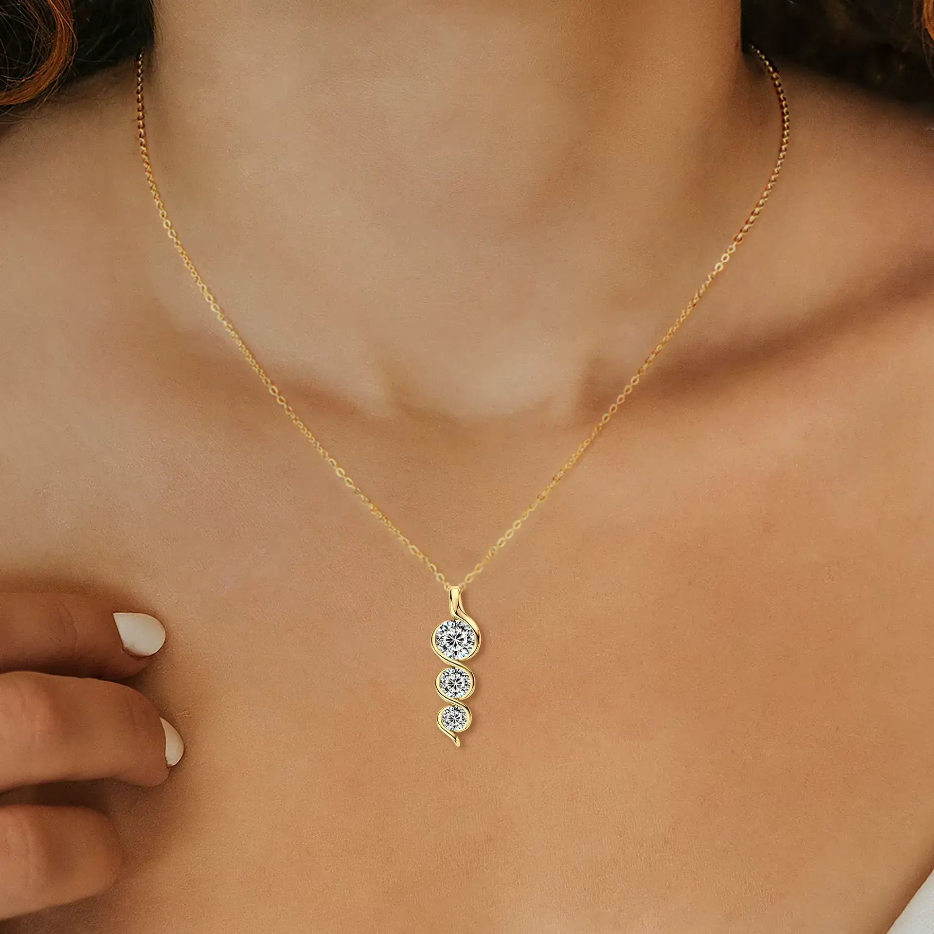 Pendentif torsadé en or jaune et diamants synthétiques porté au cou d'une femme.