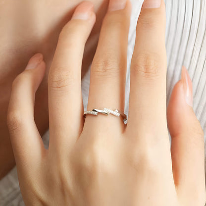 Alliance asymétrique en acier inoxydable et or blanc sertie d'oxydes de zirconium portée au doigt d'une femme vue du dessus.