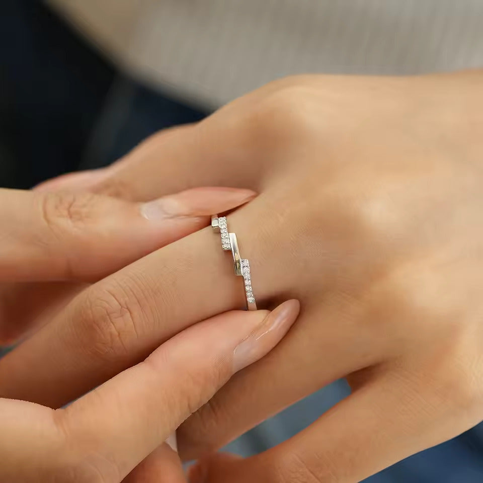 Alliance asymétrique en acier inoxydable et or blanc sertie d'oxydes de zirconium portée au doigt d'une femme.