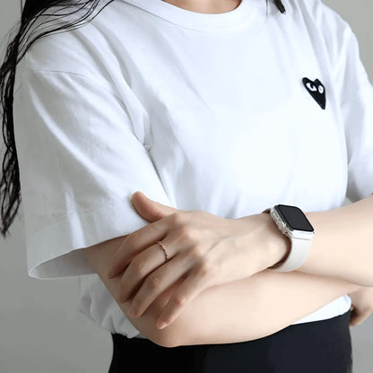 Alliance asymétrique en acier doré et oxydes de zirconium portée au doigt d'une femme vue de loin.