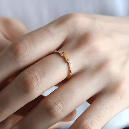 Alliance asymétrique en acier doré et oxydes de zirconium portée au doigt d'une femme.