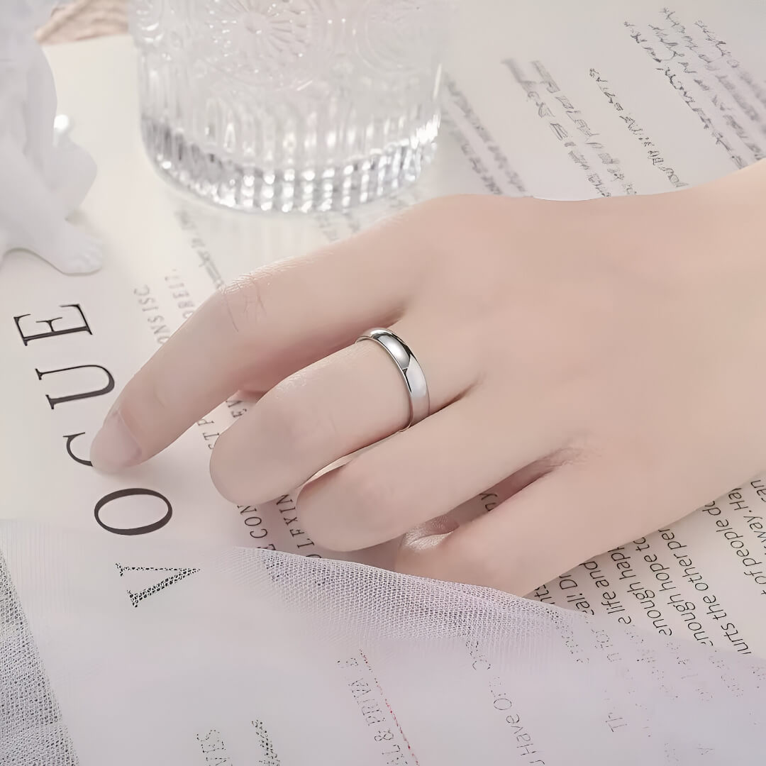 Alliance classique de mariage en acier blanc portée au doigt d'une femme.